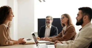 A group of professionals in a meeting discussing modern leadership strategies in a bright office environment.